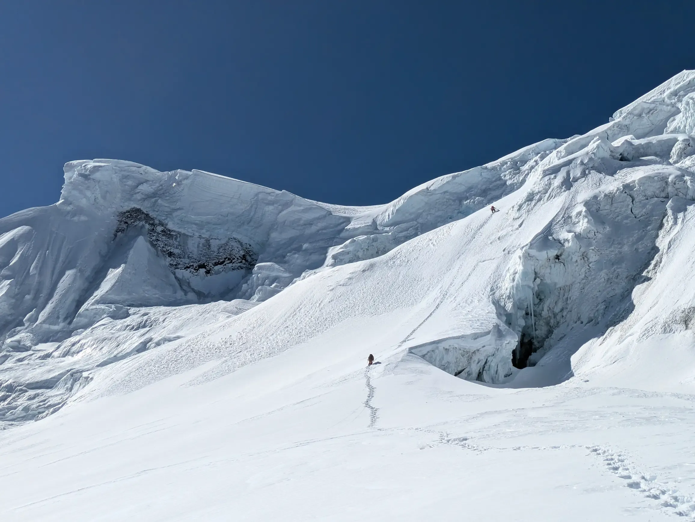 A trekker on a high mountain trail with big peaks behind